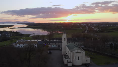 aerial of clarinbridge church rooftops and sunset sky casting warm tones over the townscape in ireland