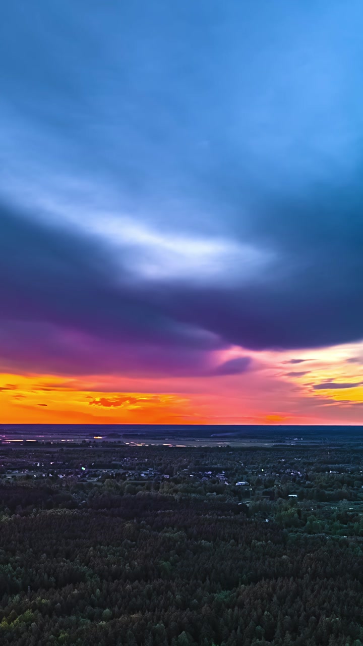 Vibrant sunset over forest horizon captured as a timelapse in vertical view