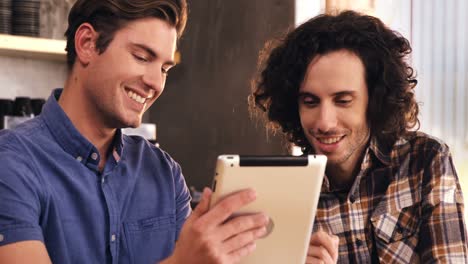 dos hombres usando tableta digital en una cafetería