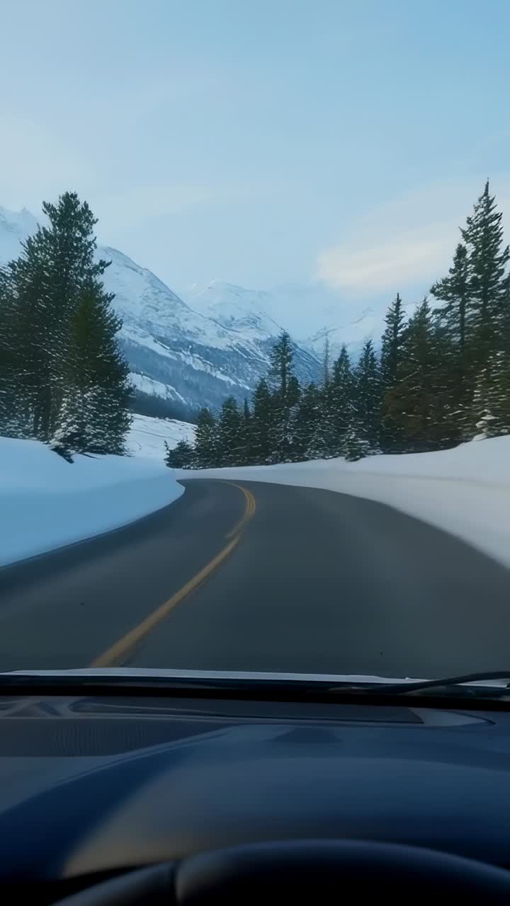 Vertical video: Driving vehicle starting along cleared mountain road, approaching snow peak, dash