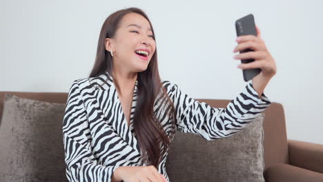 happy asian woman on video call with smartphone, waving to caller, slow motion, full frame