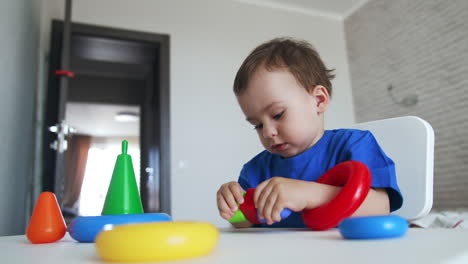 happy little boy plays cheerfully with colorful toys. child is busy with a few different toys at once.