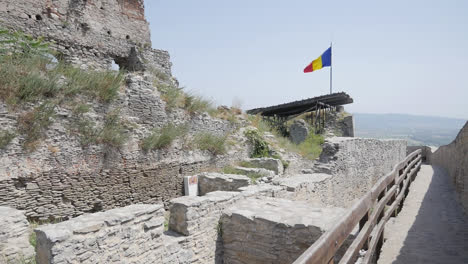castle rampart with stone barrier and distant flag waving under sunny blue sky