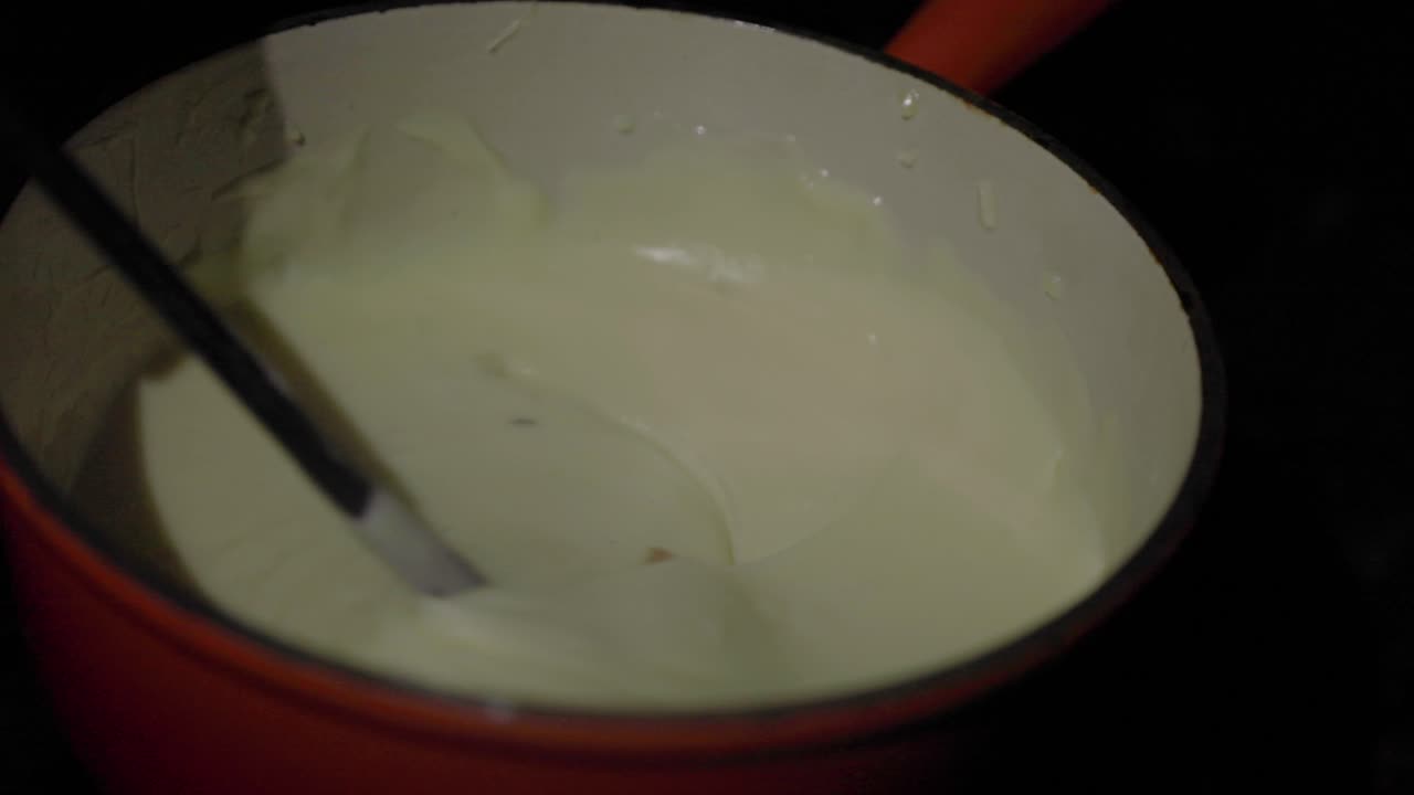 Gros plan au ralenti, du pain trempant dans un caquelon à fondue rempli de fromage