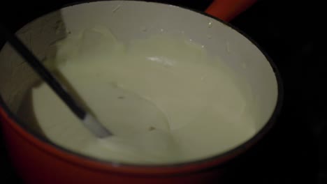 slow motion close up, dipping bread into fondue bowl full of cheese