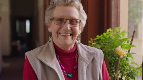 portrait of happy elderly woman standing by window smiling cheerful enjoying retirement