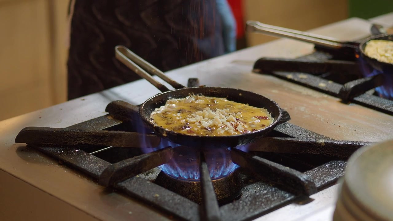 Chef che cucina un'omelette con formaggio su un fornello a gas