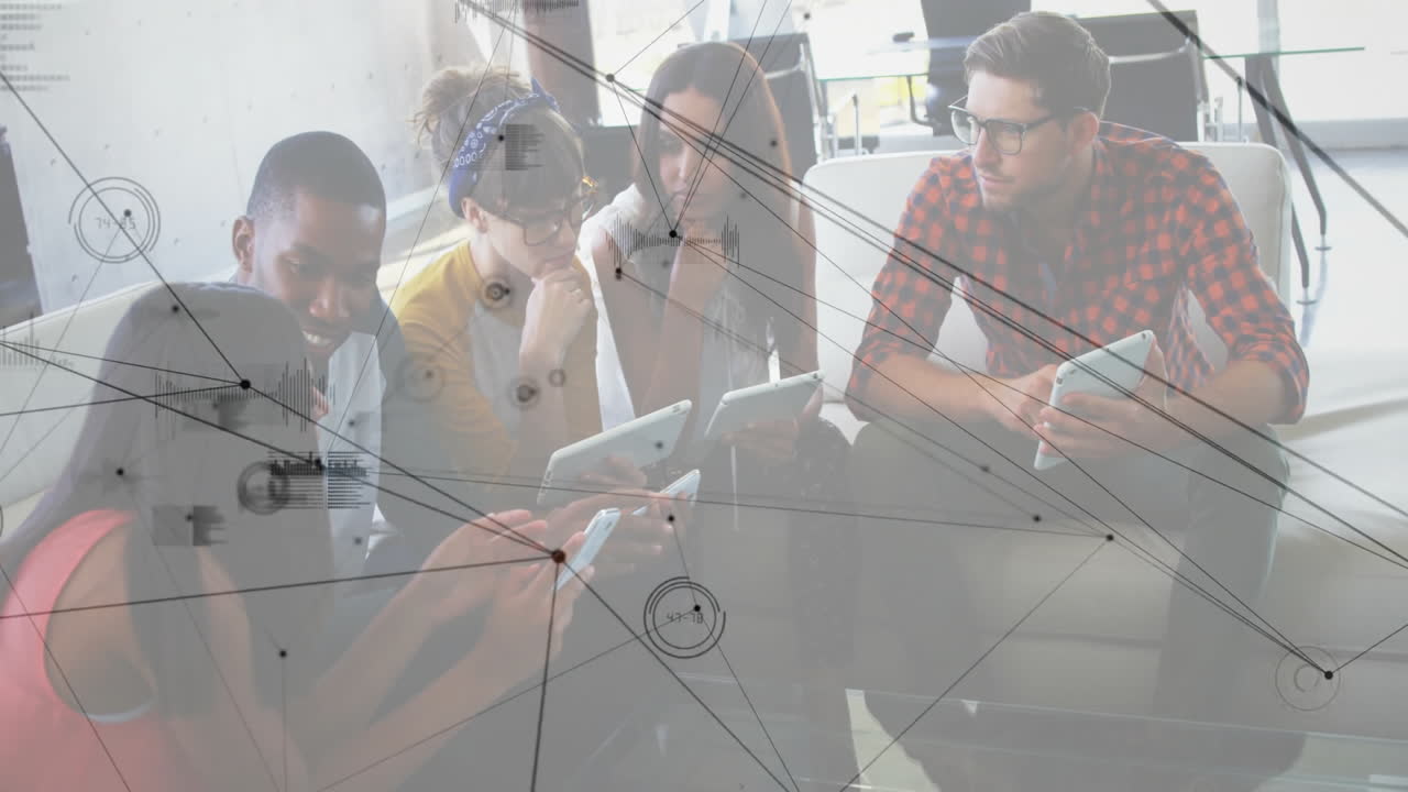 colleagues collaborating around table in lounge, using devices with network charts for technology