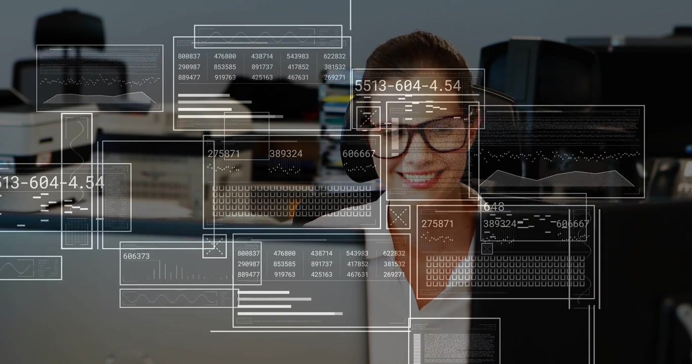 Tracking office worker wearing blazer and glasses as HUD overlays appear at monitor monitoring data