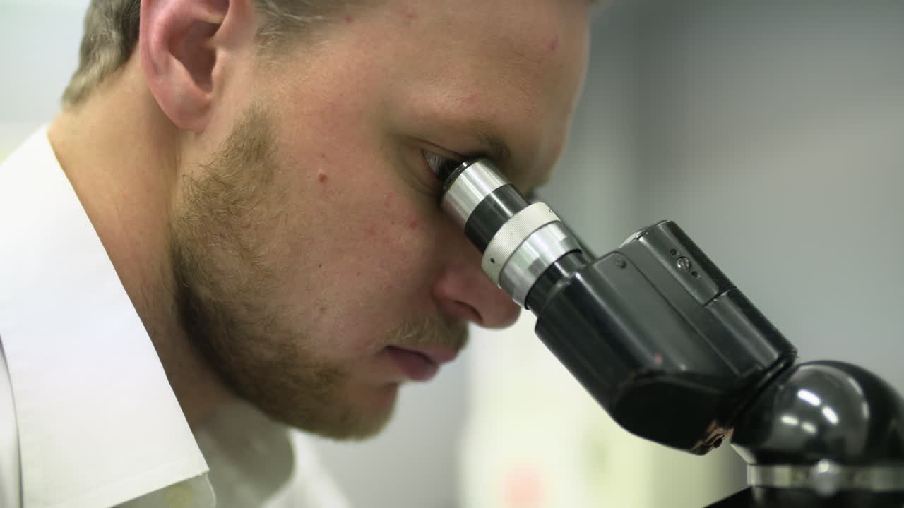 Primo piano di un uomo che guarda al microscopio in un laboratorio.