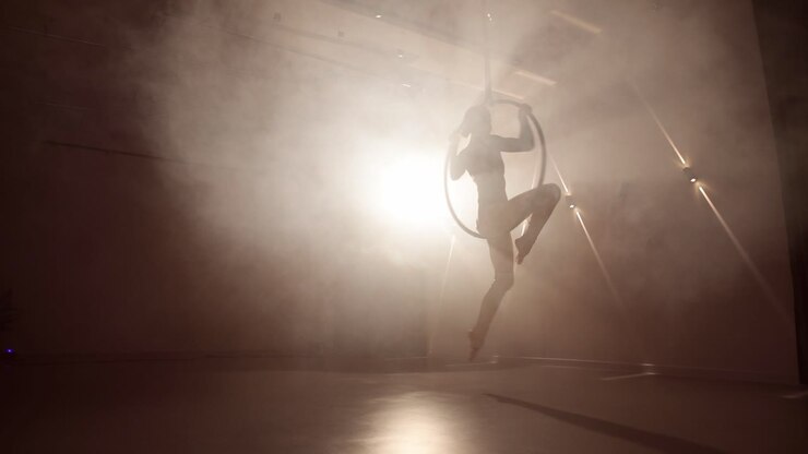 Aerial hoop female dancer performing in a smoky room