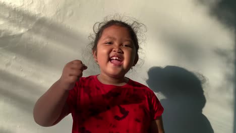Glückliches-Asiatisches-Kleines-Mädchen,-Das-Steht-Und-Die-Hände-Ballt