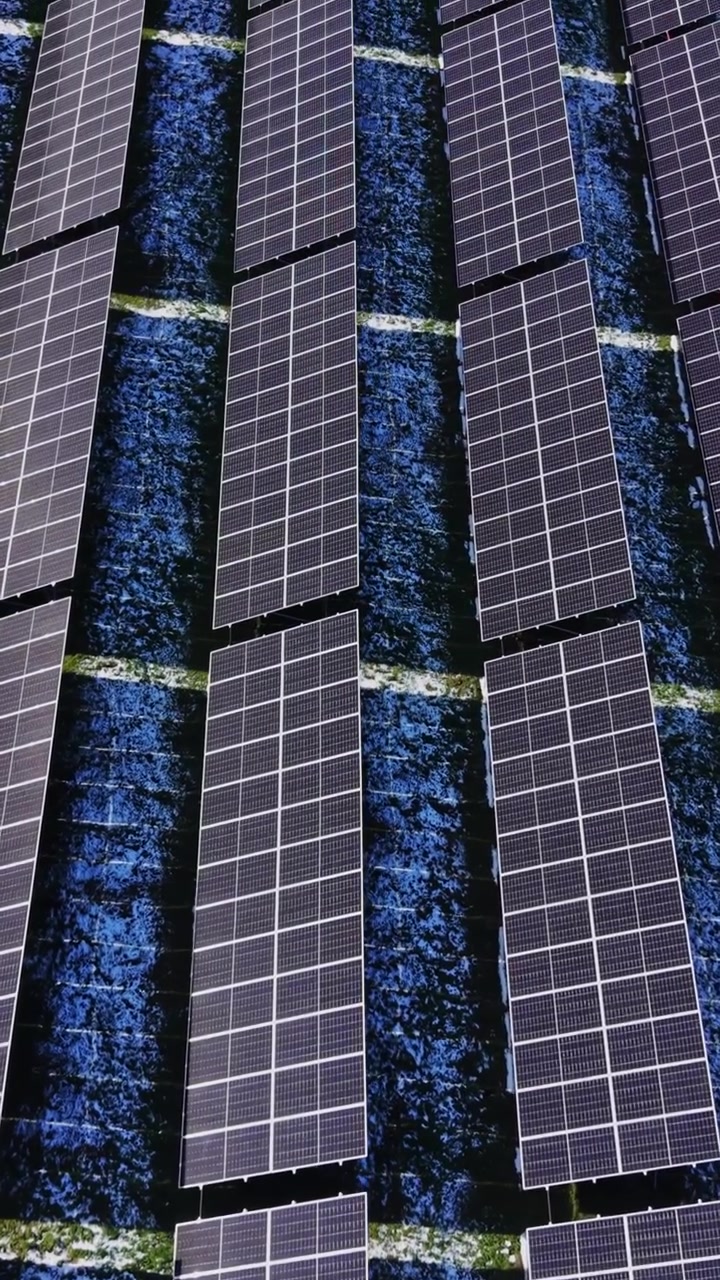I pannelli solari coprono il terreno in un sito di energia rinnovabile vicino a un campo.