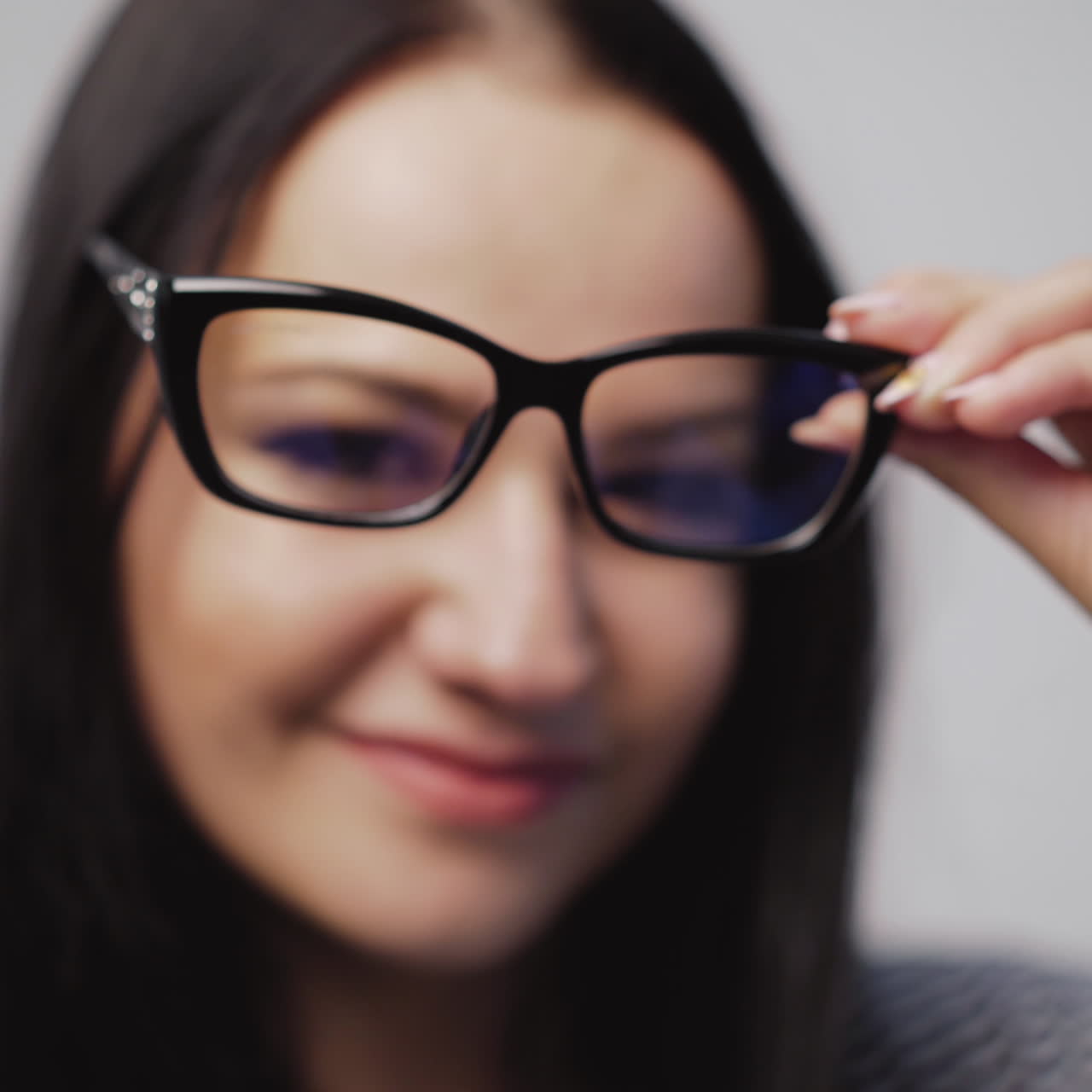 Fashionable eyeglasses close-up on the blurred background of a woman. Woman shows and then puts on new glasses in black rim.