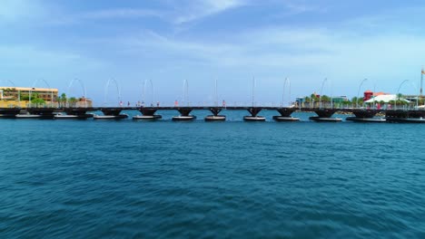 4k-drone-shot-of-the-floating-pontoon-Queen-Emma-Bridge,-tourists-and-pedestrians-walking-over-it