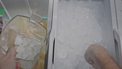 a man collects ice from the icemaker of a domestic refrigerator