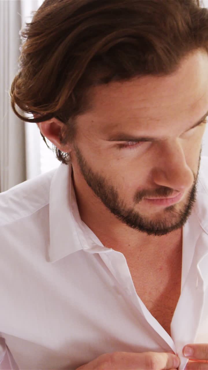 침실에서 옷을 입고 있는 남자