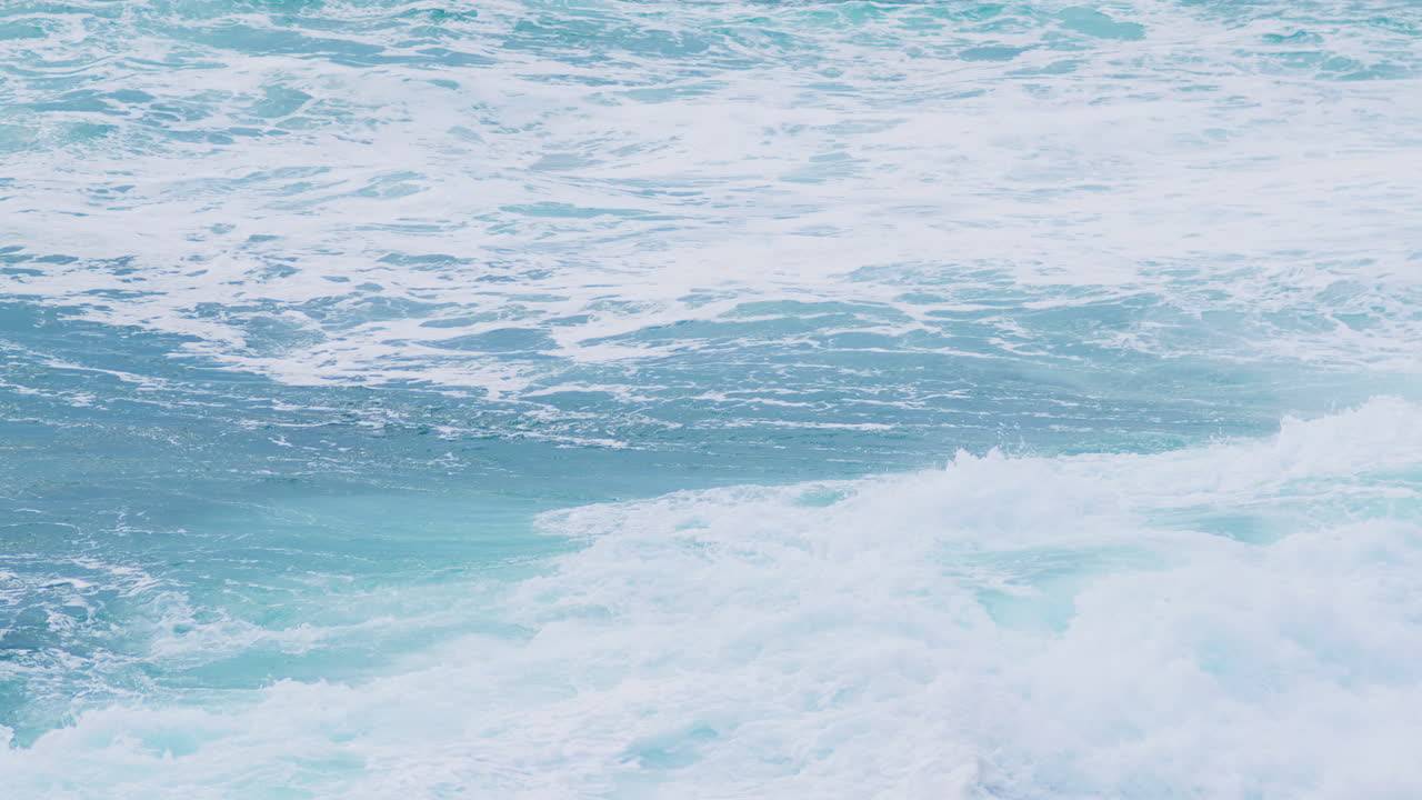 強風時に海岸線近くで大きな波が砕け、泡と霧が発生する