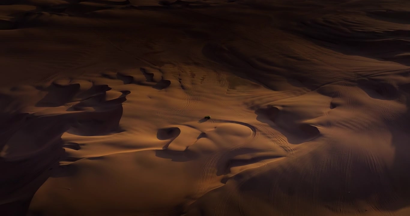 Ombre drammatiche e luce dorata sulle dune di sabbia con tracce di buggy nel deserto di Huacachina, Perù, drone in ascesa orbitale
