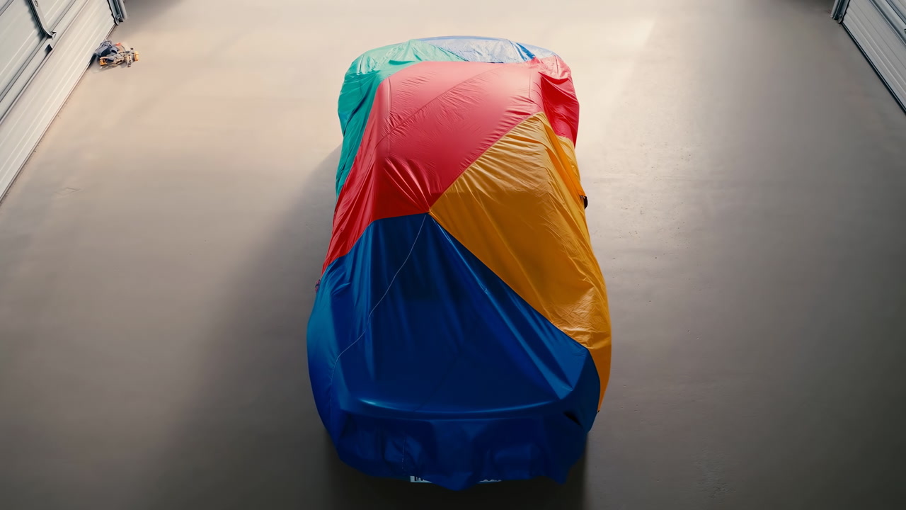 Colorful Car Covered In Garage, Mysterious Atmosphere With Soft Overhead Lighting, Multicolor Fabric Draped