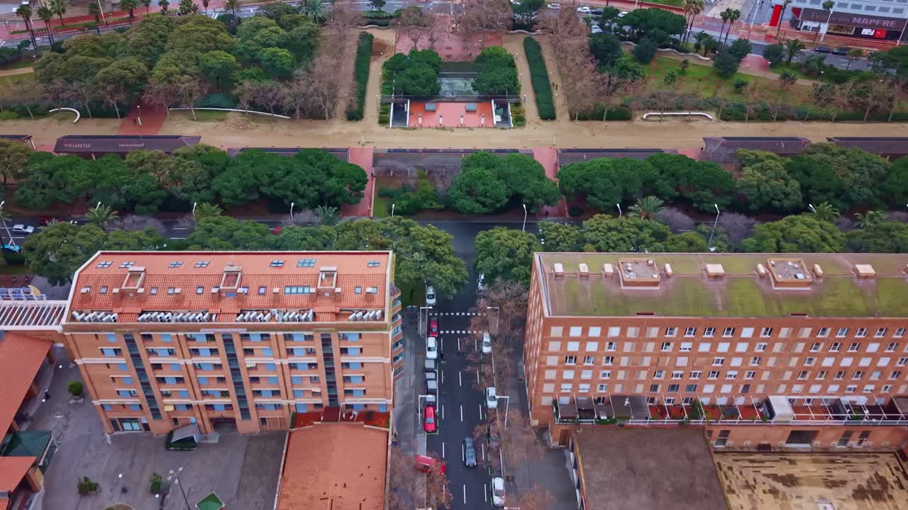 Volo in planata di drone dall'alto tra edifici residenziali a Vila Olímpica del Poblenou, Barcellona, che rivela l'asse verde e la disposizione del parco urbano Parc de la Nova Icària