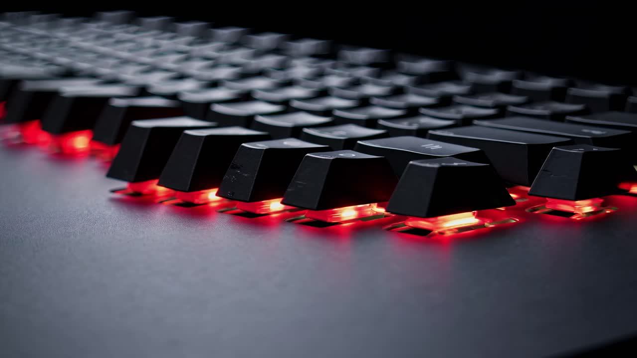 Close-up, low-angle shot of a backlit keyboard with red lighting, emphasizing a futuristic