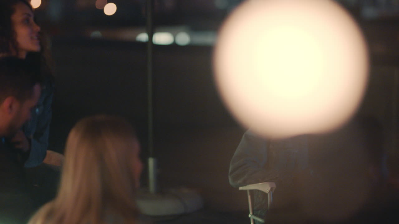 grupo de amigos viendo una película en el cine de la azotea pasando el rato juntos disfrutando de una fiesta de reunión de fin de semana en la ciudad urbana por la noche