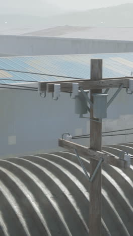 a wooden utility pole with power lines running through it, in front of an industrial building