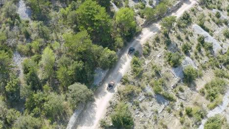 aerial of buggy cars riding on rough and unpaved terrain amidst barren land