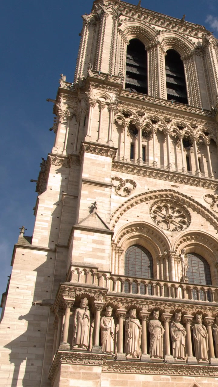 Inquadratura inclinata dal basso della ricca facciata gotica e delle statue della Cattedrale di Notre Dame.