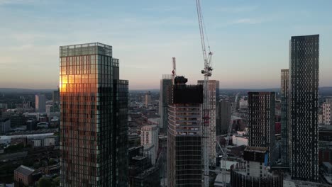 Luftdrohnenflug-In-Manchester-Um-Deansgate-Türme-Und-Neubau-Von-Hochhäusern-Mit-Sonnenuntergang-Im-Spiegel-Des-Glases