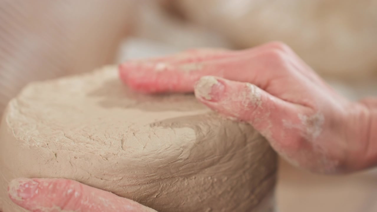 Closeup white potter smoothing clay, delicate fingertip shaping of moist cylinder, textured surface, hands dusted with clay, tactile meditative studio atmosphere, pottery workshop focus on technique