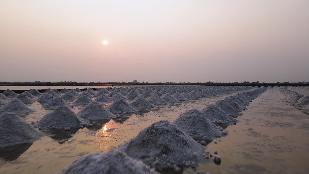 Impresionante toma baja de dron con puesta de sol en Tailandia de pilas de sal marina, Phetchaburi