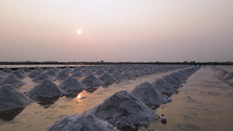 Malerische-Niedrige-Drohnenaufnahme-Mit-Sonnenuntergang-In-Thailand-Von-Meersalzhaufen,-Phetchaburi