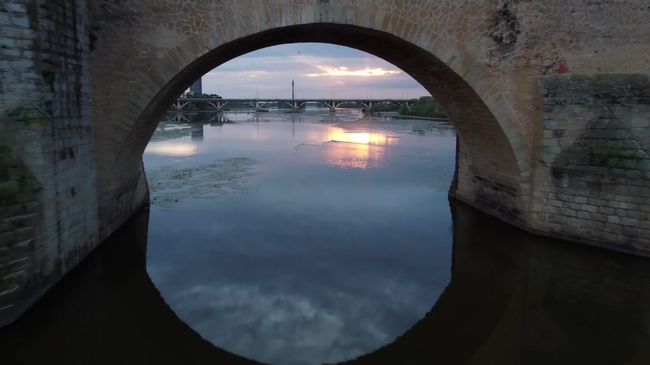 Scenic Sunset View Of Puente de Palmas Across Guadiana River In Badajoz, Spain. drone approach