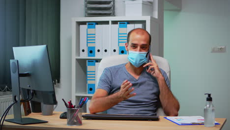 freelancer con máscara hablando por teléfono móvil