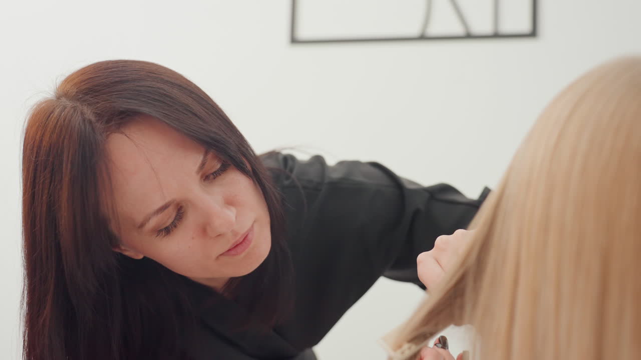 Primer plano de peluquero recortando pelo rubio, escena de estudio enfocada que muestra una técnica de corte profesional, manos delicadas que alinean la longitud, movimiento preciso de tijeras y peine, iluminación neutra cálida, moderno