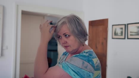 Fat-woman-with-short-grey-hair-standing-in-front-of-the-mirror-styling-her-hair-with-a-hairspray-covering-her-face-in-an-old-European-apartment