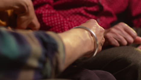 Close-Up-Of-Multi-Generation-Male-Sikh-Family-Wearing-And-Discussing-Traditional-Silver-Bangles-Or-Bracelets-Sitting-On-Sofa-At-Home