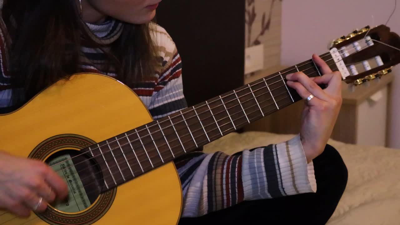 chica de cerca practicando guitarra en la cama