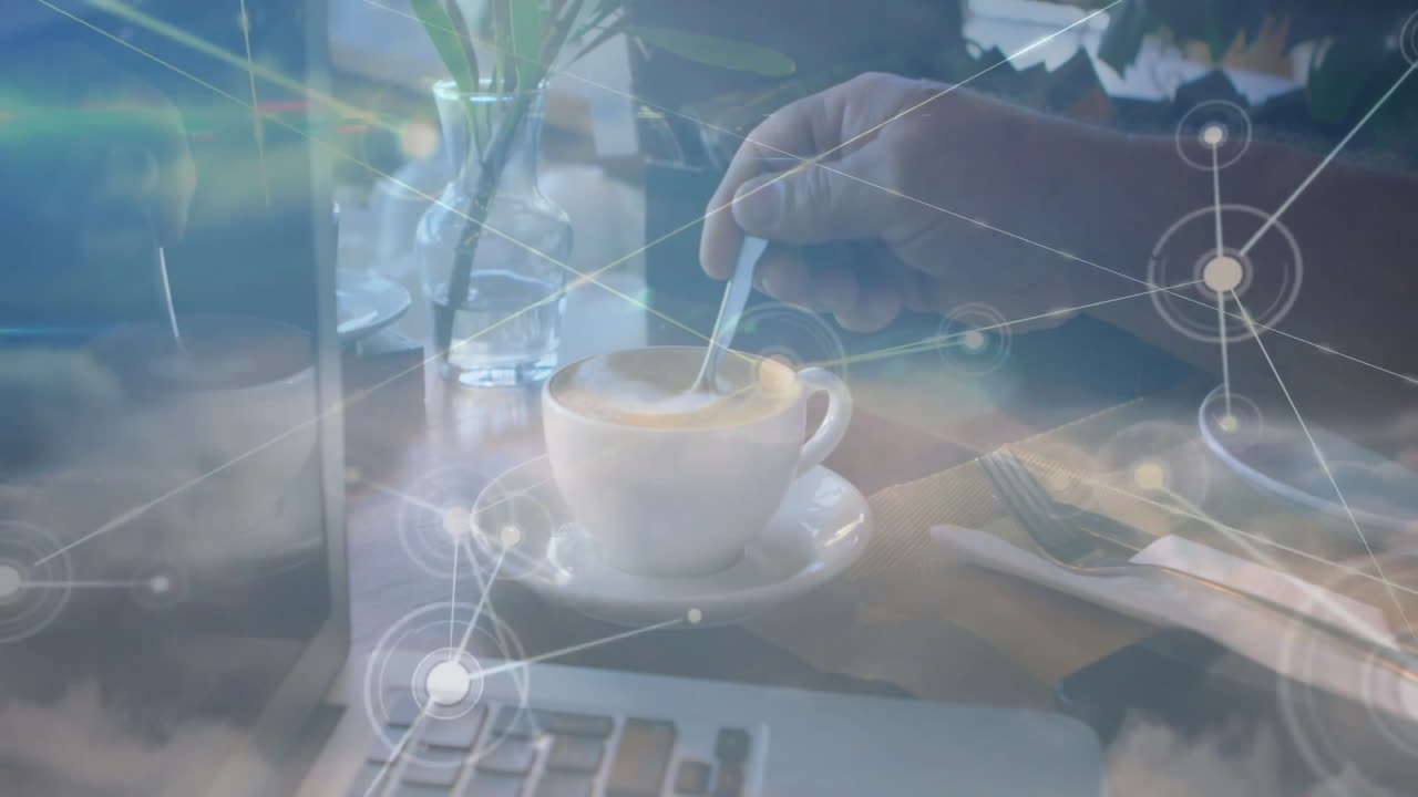 Man stirring coffee on wooden table, blending laptop view with tech network graphics
