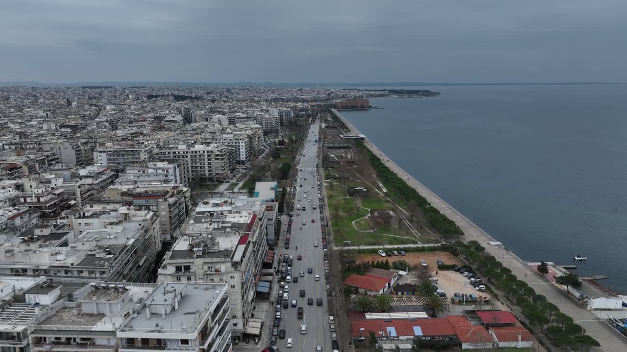 Frontal traveling shot of the waterfront of the big city Thessaloniki on a cloudy day, Greece. People commuting.