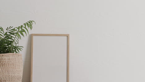 wooden frame with copy space on white background with plant on desk against white wall