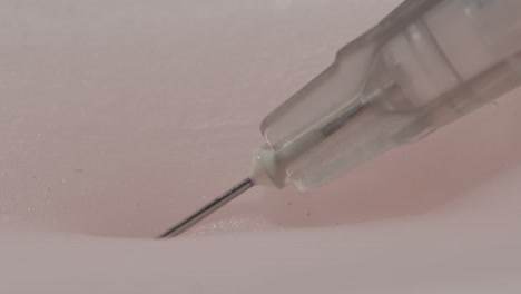 macro view of a syringe penetrating human skin as a patient receives a vaccination