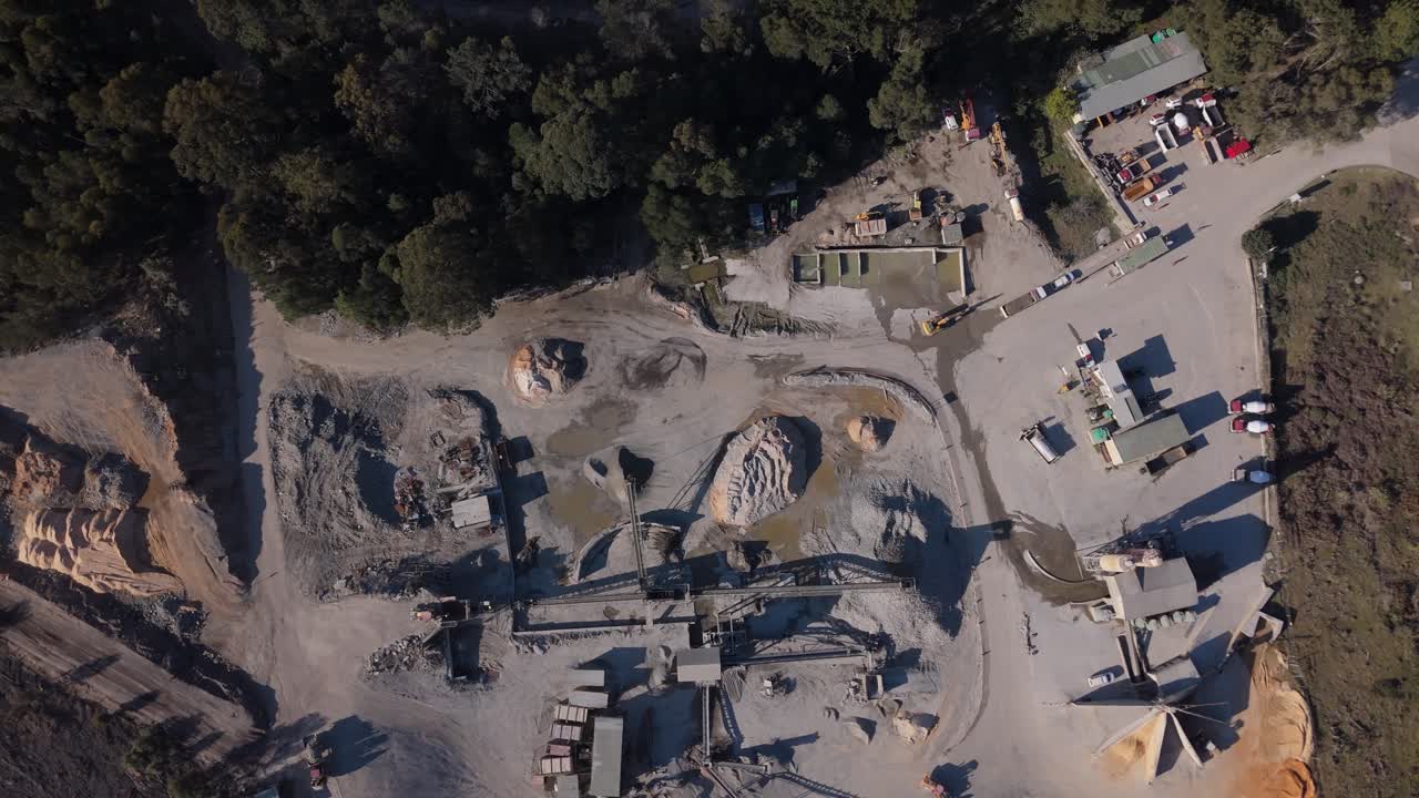 4K drone view looking directly down over a full quarry site with machinery, roads, and exposed earth, South Africa