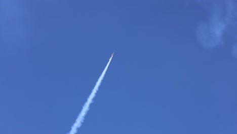 a rocket ascends through clear blue sky