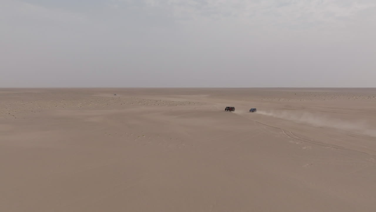 Two cars driving through the desert toward Bar al Hikman, Oman, aerial view