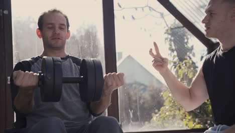 disabled man in wheelchair working out with dumbbell at home while his personal trainer motivating him 1