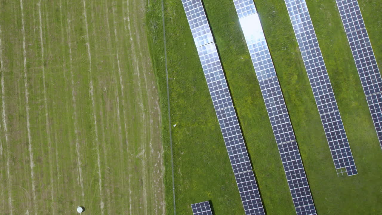вид с воздуха на солнечные батареи на зеленом поле прямо вверху