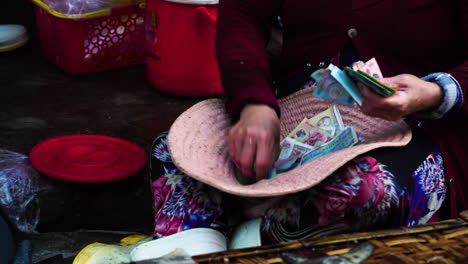 escena callejera vietnamita, mujer contando dinero dentro de un gran sombrero